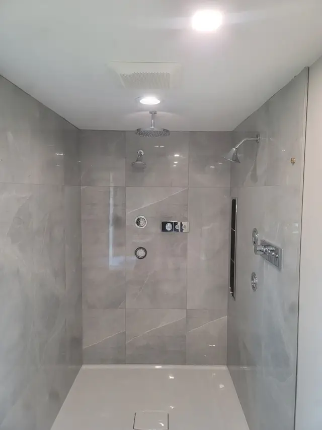 Walk-in shower with large-format grey tile and frameless glass