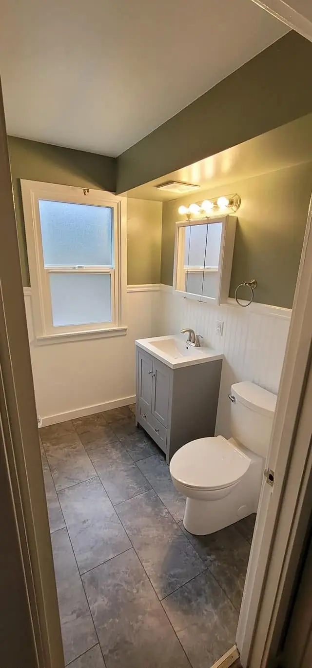 Bathroom with a grey vanity, an olive wall and a slate floor