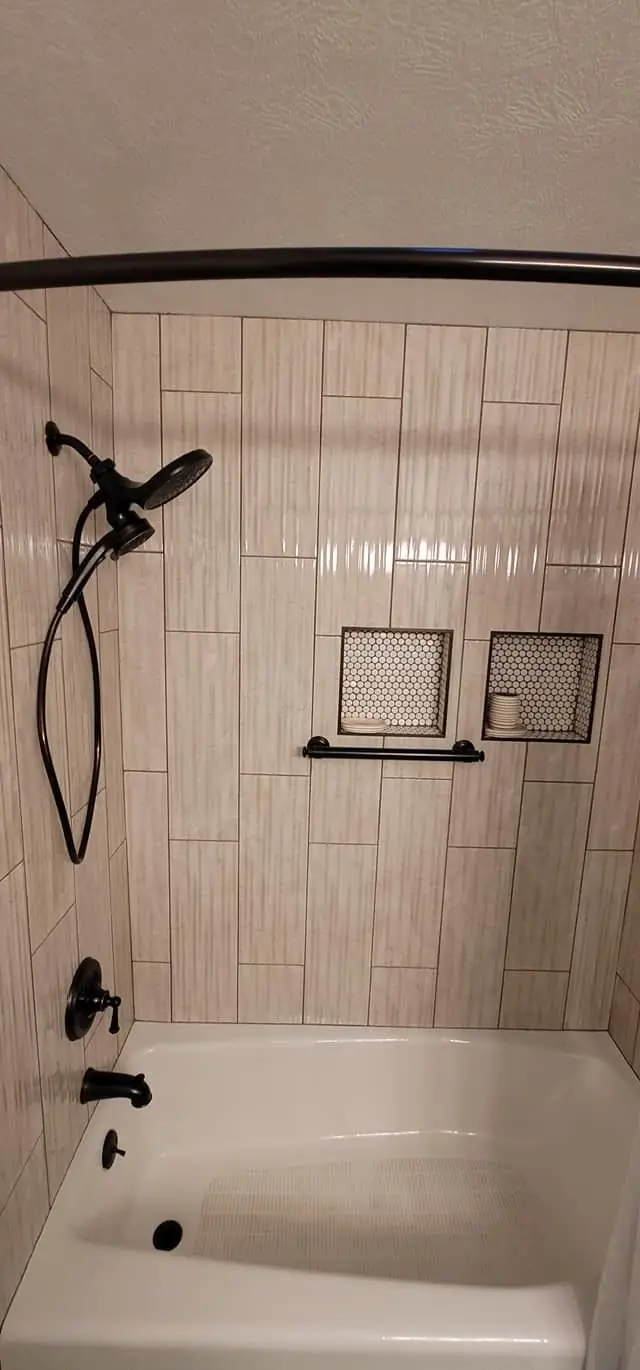 Bathroom tub and shower with vertical tile and bronze fixtures