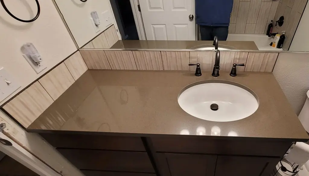 Bathroom vanity with a taupe quartz top and an oil-rubbed bronze faucet