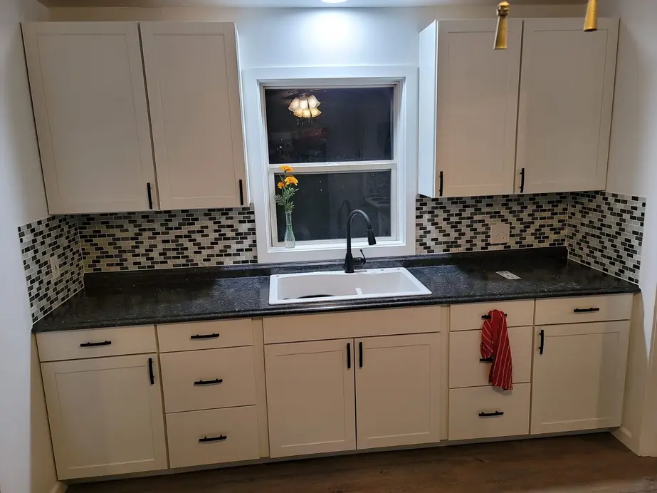 White shaker kitchen with a mosaic tile backsplash and dark counters