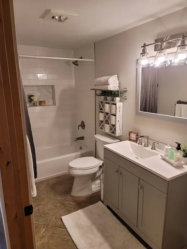Finished bathroom with a tub, a grey vanity and vanity lights